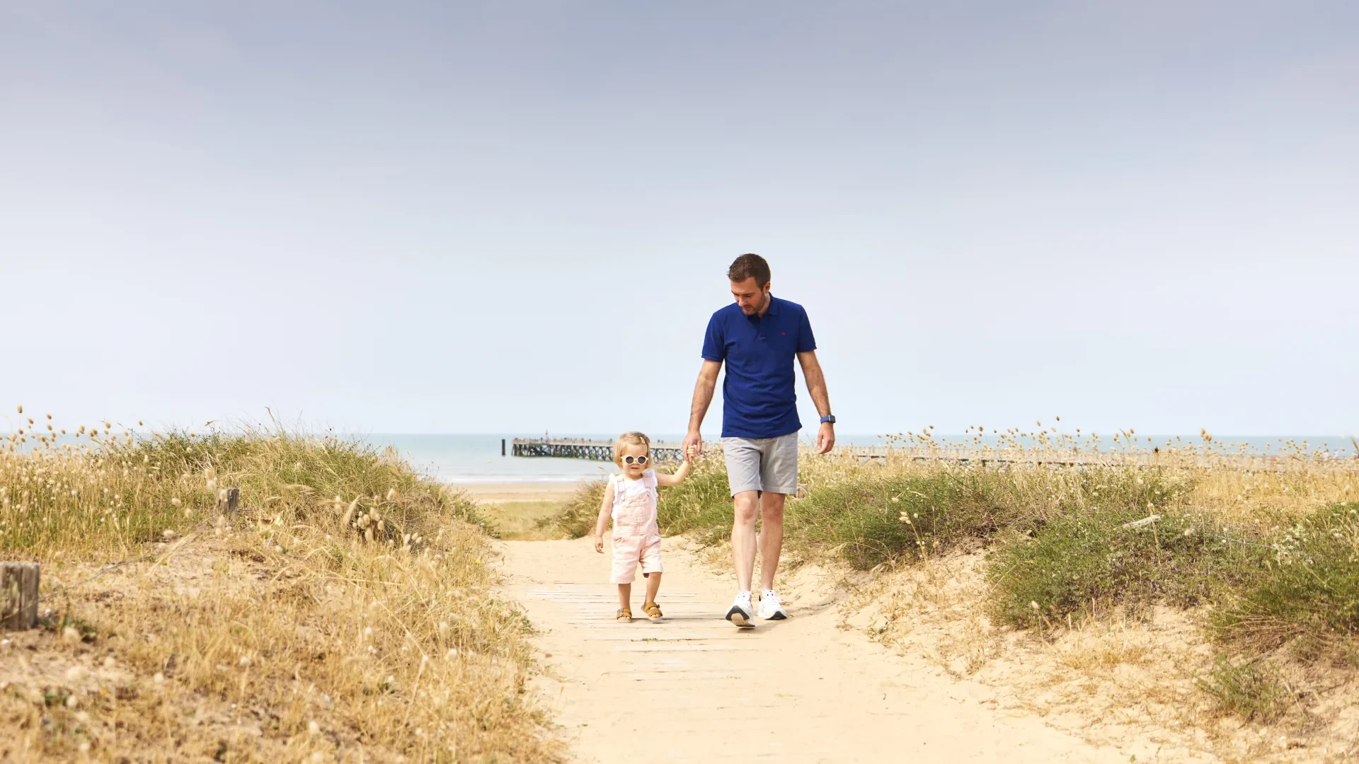 Foto von einem Vater und seinem Kind, die auf der Düne von Saint Jean de Monts spazieren gehen