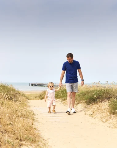 Foto von einem Vater und seinem Kind, die auf der Düne von Saint Jean de Monts spazieren gehen